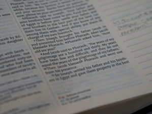 Close-up view of a book page containing English text, likely from a religious or historical book, possibly the Bible. The text appears to be part of a narrative. There is handwritten text visible on the right side, in the margin next to lines meant for notes.