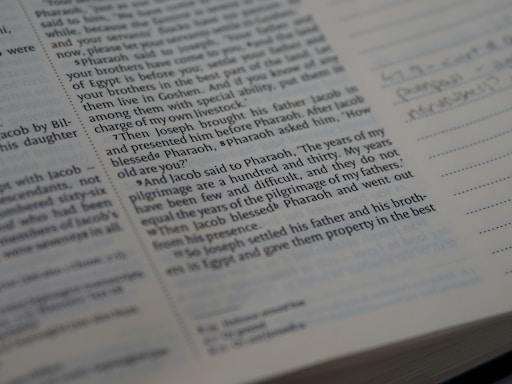 Close-up view of a book page containing English text, likely from a religious or historical book, possibly the Bible. The text appears to be part of a narrative. There is handwritten text visible on the right side, in the margin next to lines meant for notes.