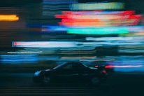 A fast-paced racing game scene showing sleek cars speeding through a neon-lit city at night.