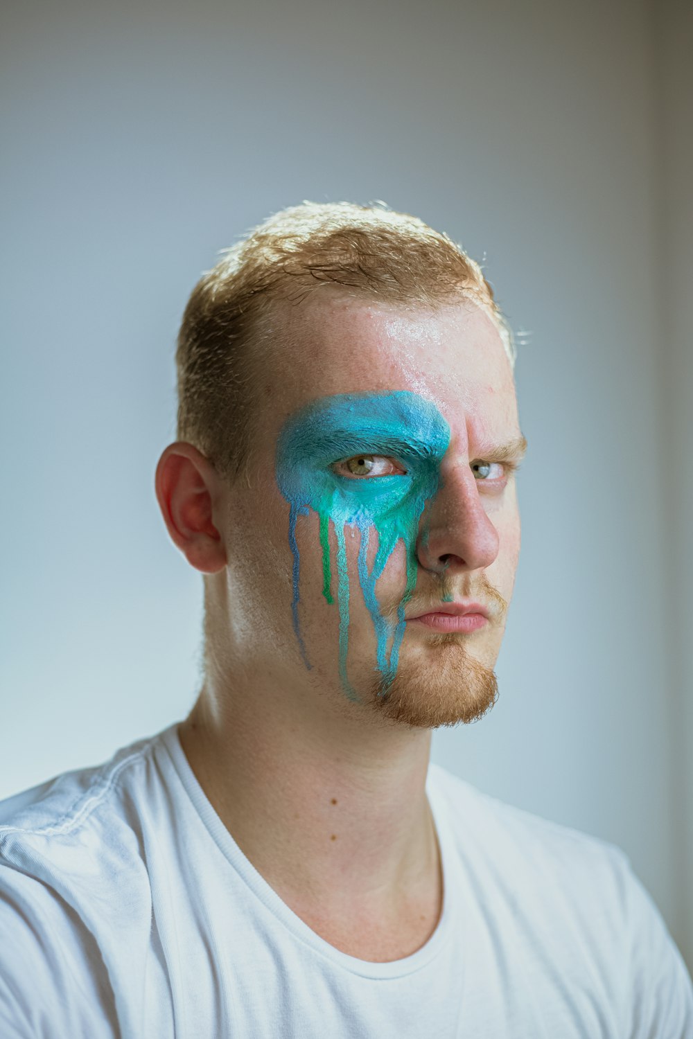 man in white crew neck shirt with blue green and red face paint