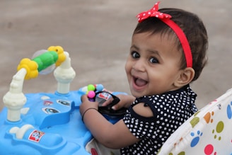 girl in black and white polka dot shirt with red headband sitting on white and blue