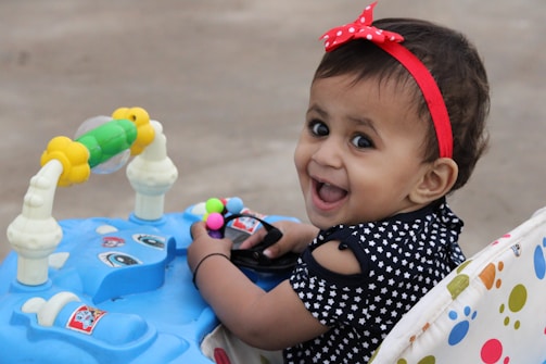 girl in black and white polka dot shirt with red headband sitting on white and blue