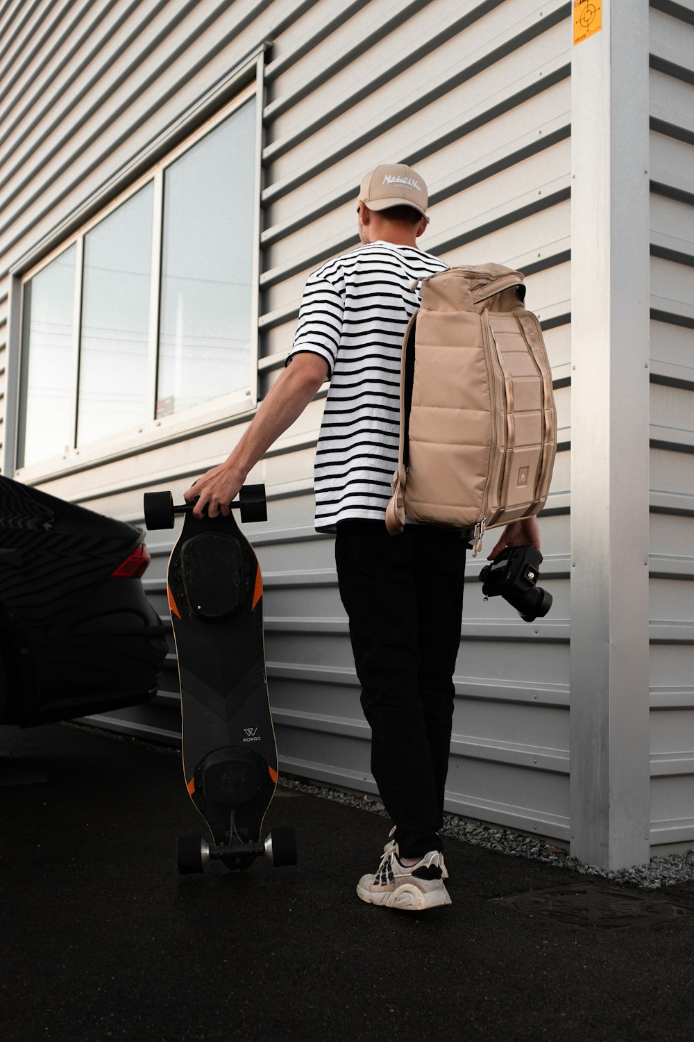 man in white and black striped shirt and black pants carrying black and brown backpack