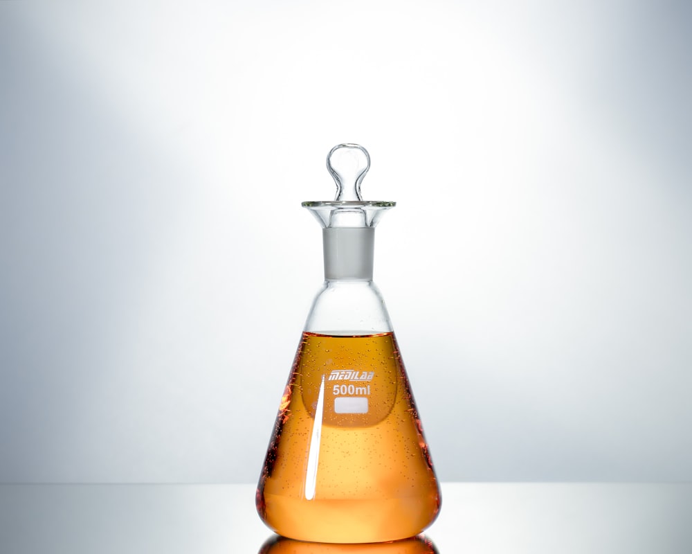 Botella de vidrio transparente con líquido marrón