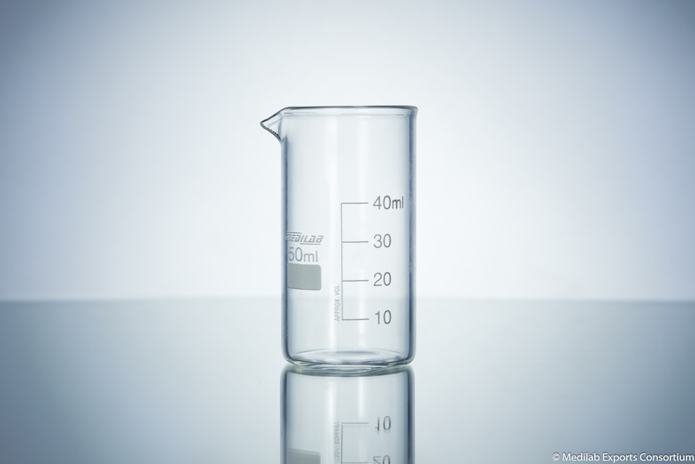 Tasse à mesurer en verre transparent sur surface blanche
