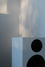 A modern speaker emitting sound waves, set against a minimalist backdrop.