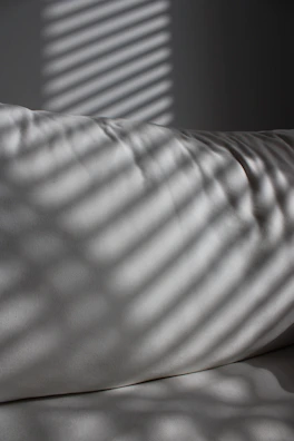 A serene composition of light and shadow on a white fabric, evoking calm movement