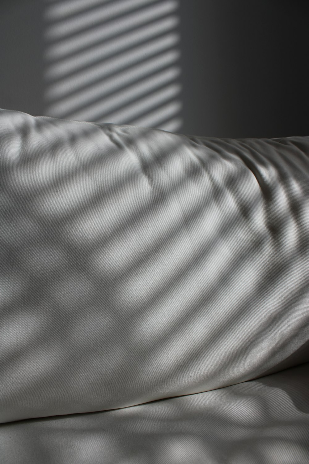 白い掛け布団と白い枕付きのベッド