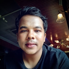 A warm, inviting portrait photo of a person smiling gently in a cozy, well-lit room.