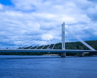 white bridge over the sea under white clouds and blue sky during daytime