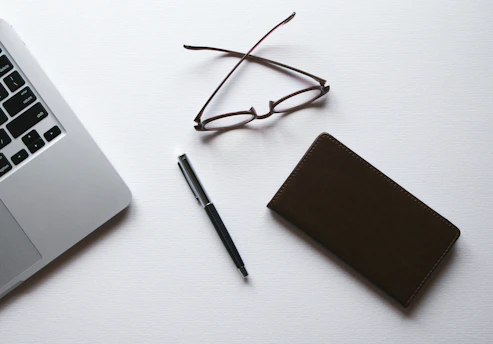 A clean, minimalist photo of a legal contract being reviewed with a laptop and notes on a bright white desk.