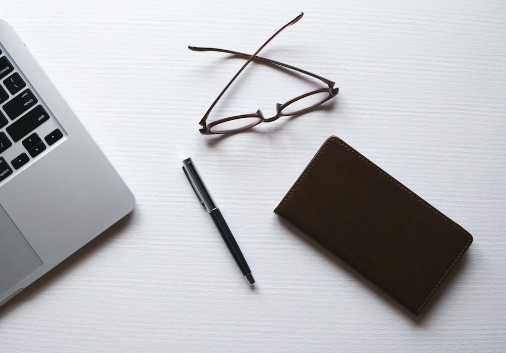 brown framed eyeglasses beside silver macbook