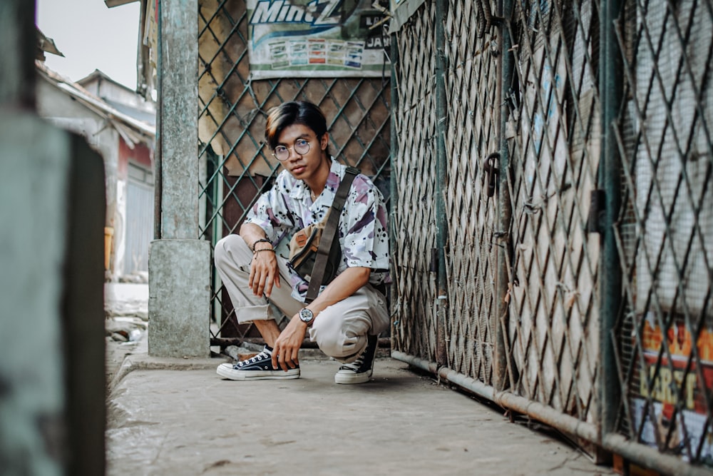 man in white and black button up shirt sitting on gray concrete floor