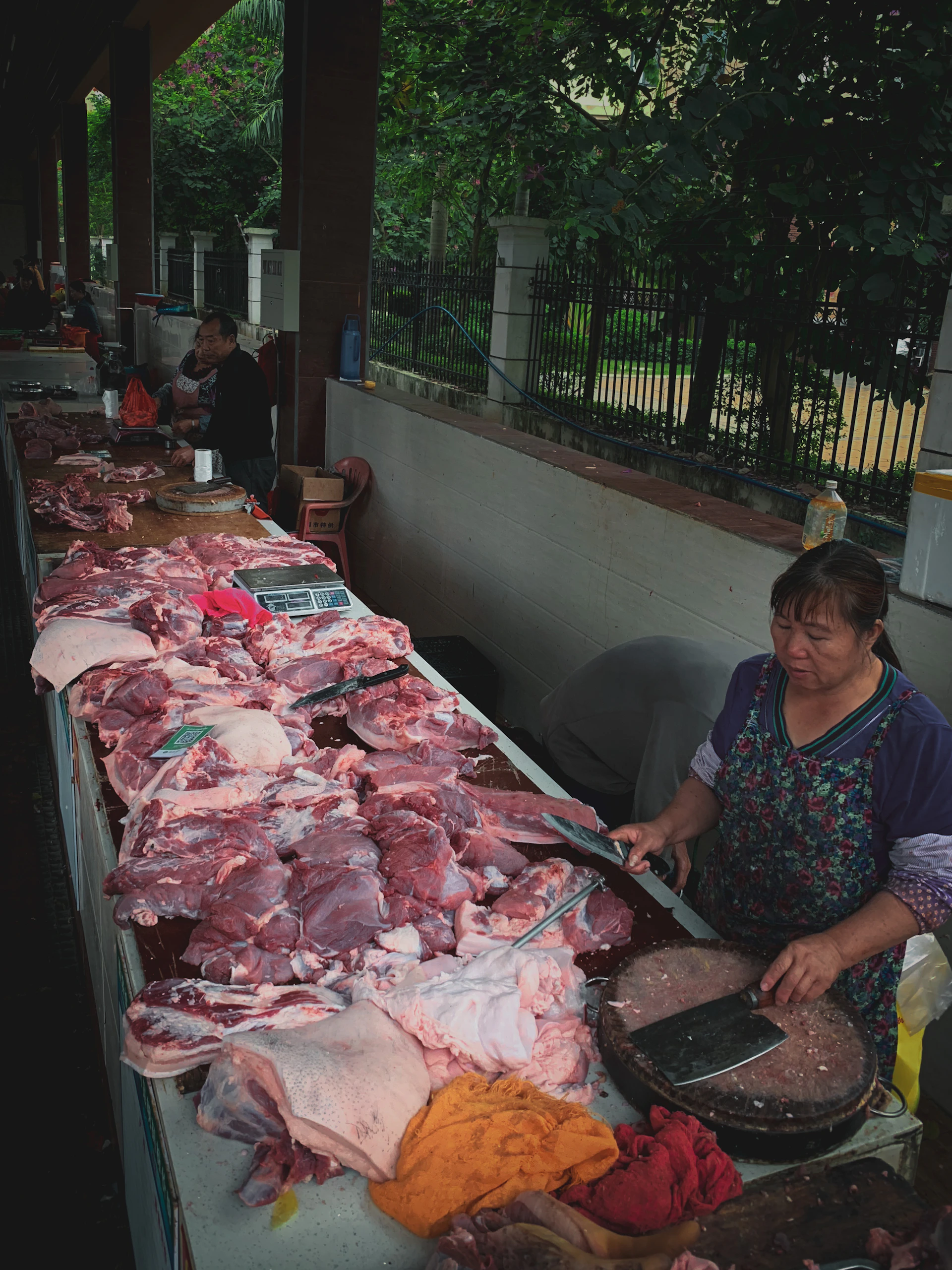 woman in black and white floral dress standing beside raw meat