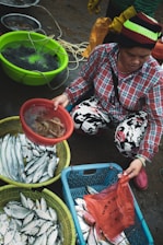 A friendly fishmonger selecting seasonal vegetables alongside fresh seafood.