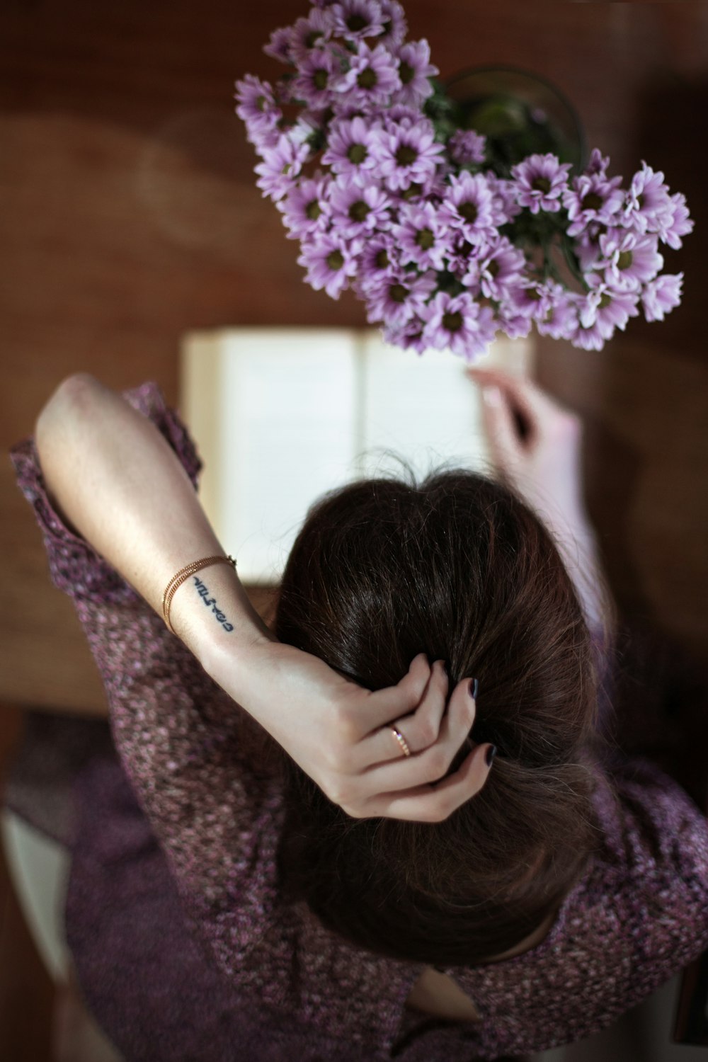 woman in purple long sleeve shirt holding purple flowers