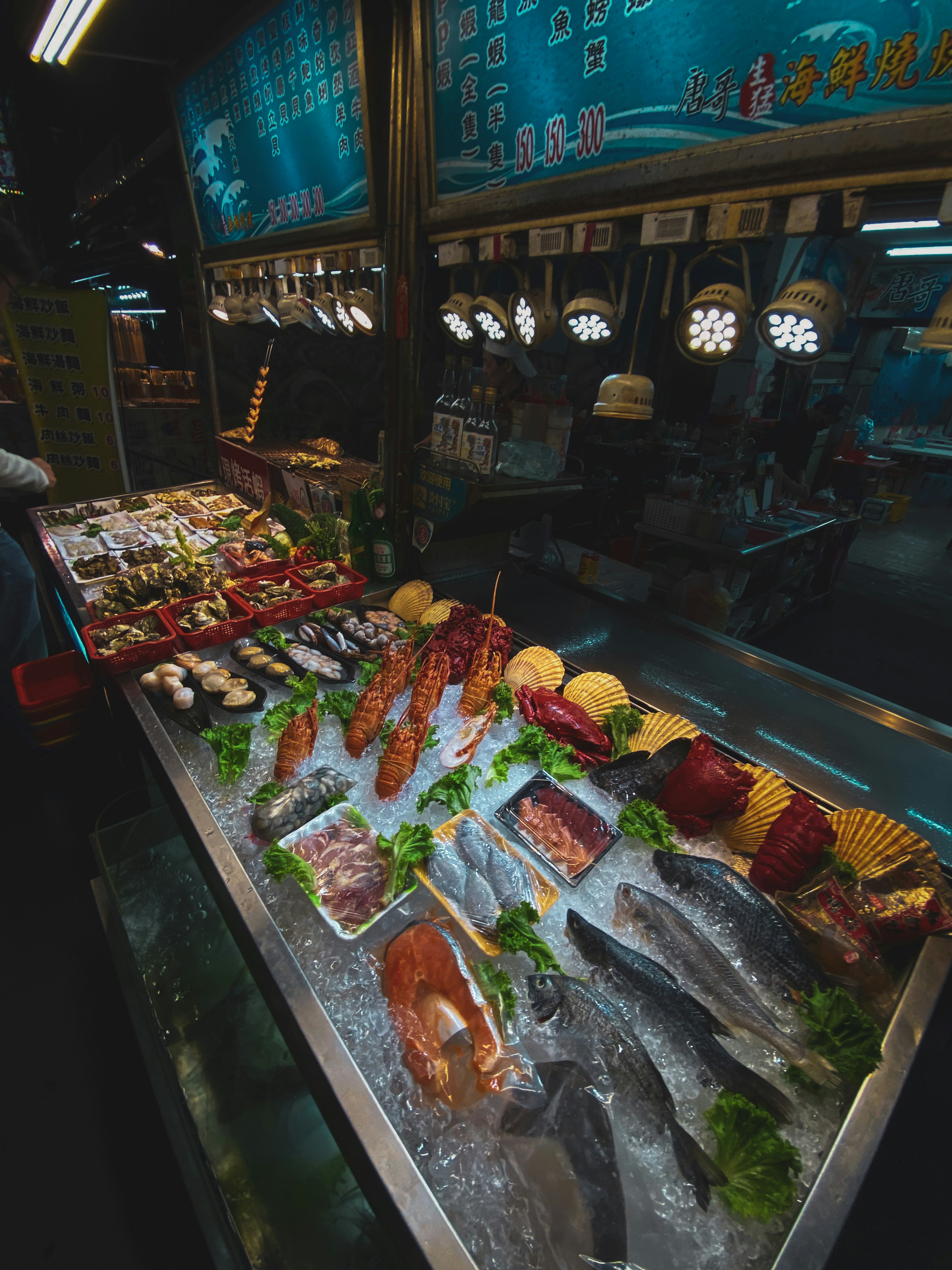 Fresh whole salmon and seafood on ice in a bright fish market, glistening silver skin under cool white lighting