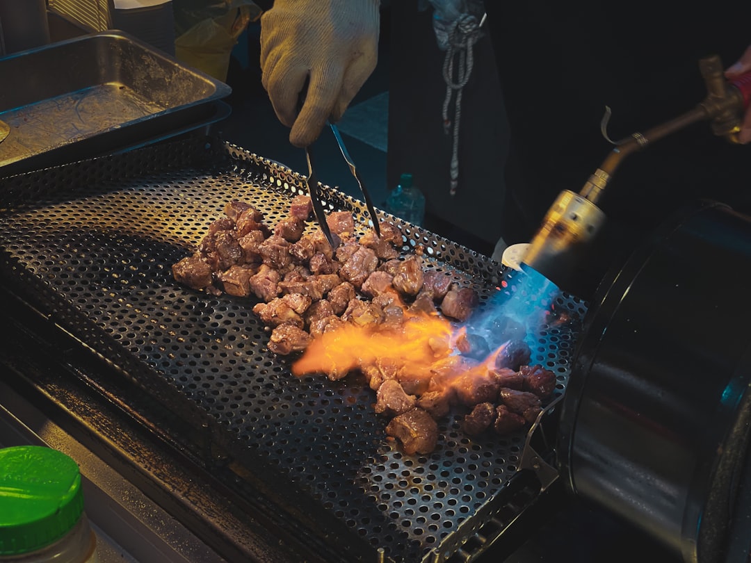 person holding knife slicing meat on grill