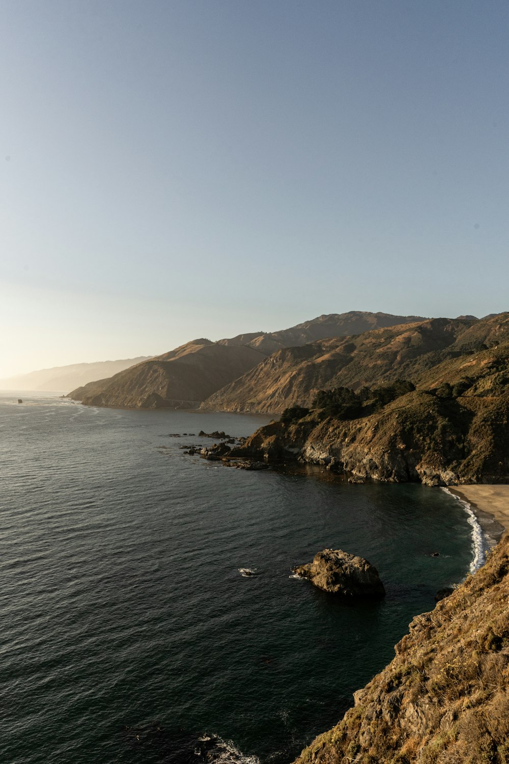 green and brown mountain beside body of water during daytime