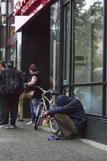 man in black jacket and blue denim jeans riding on black bicycle