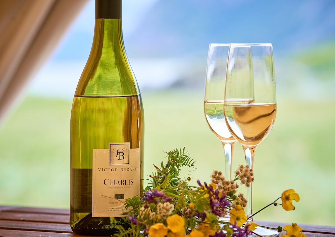 green glass bottle beside clear wine glass