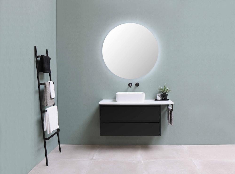 white round mirror on green wall