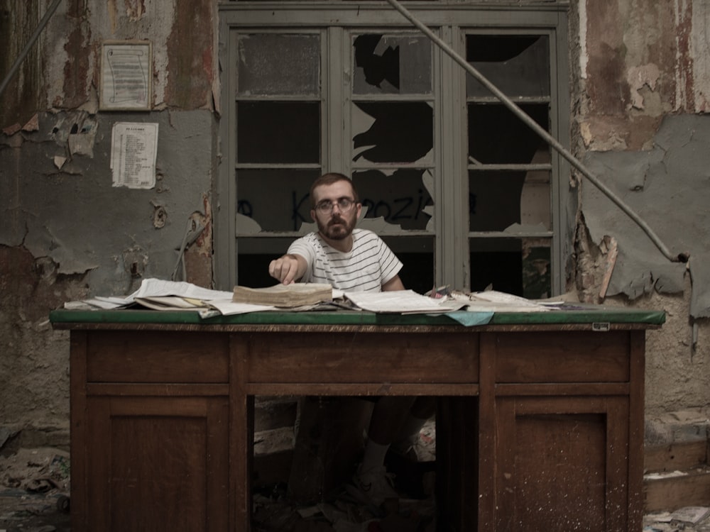 man in white and black striped shirt sitting beside brown wooden table