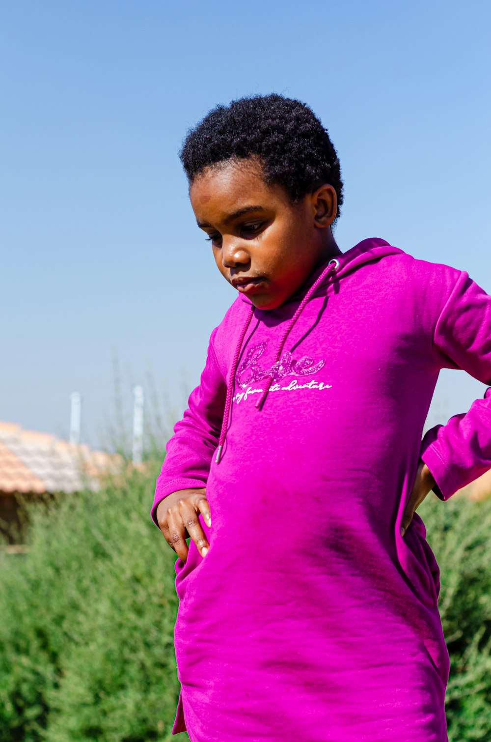 man in pink hoodie standing on green grass field during daytime