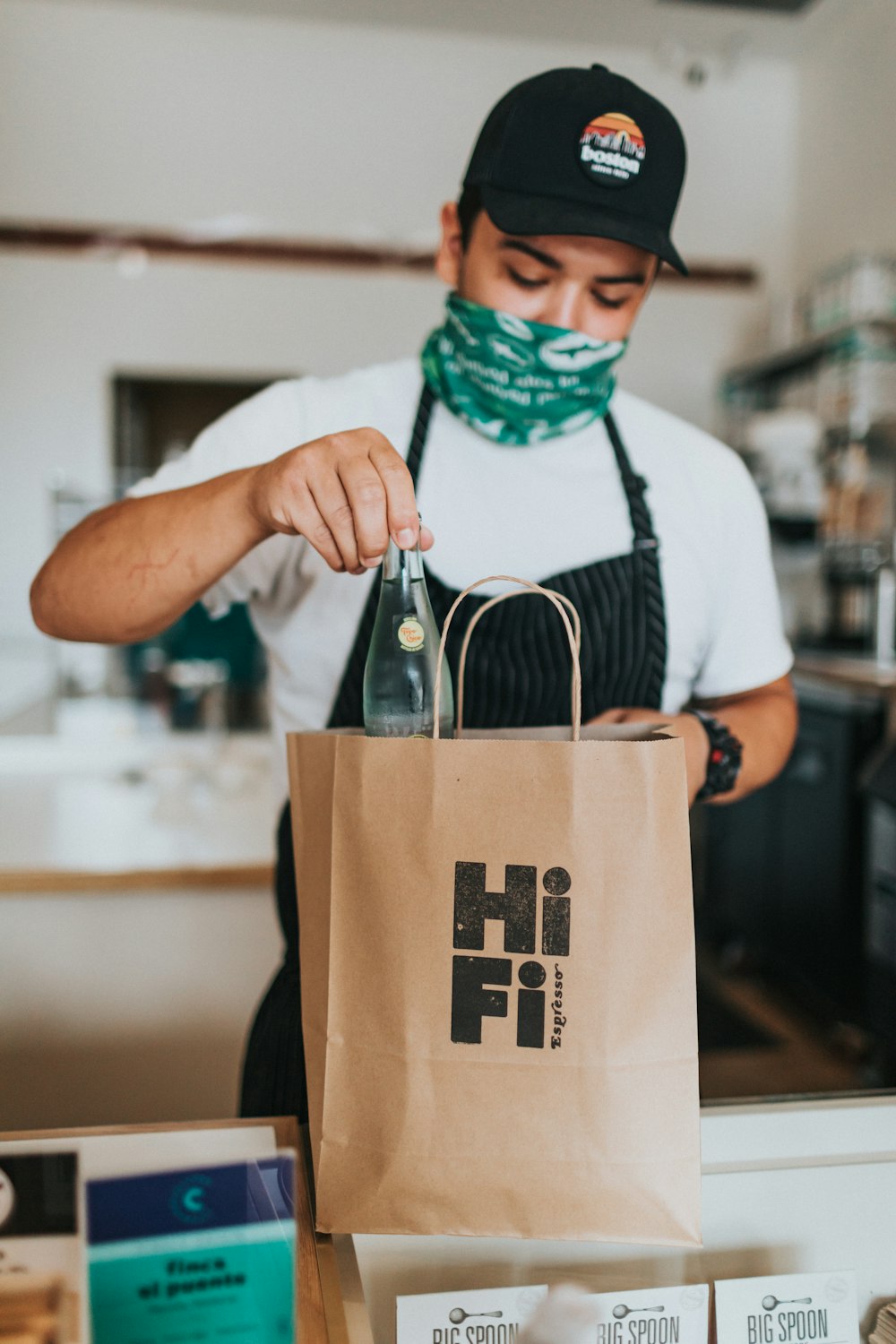 man in white t-shirt holding brown paper bag