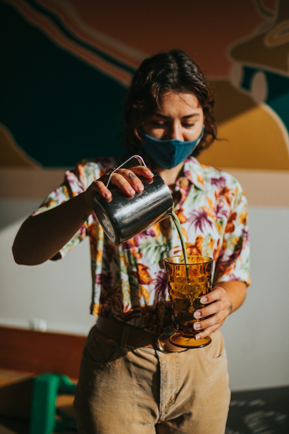 woman in blue and white floral shirt holding stainless steel cup