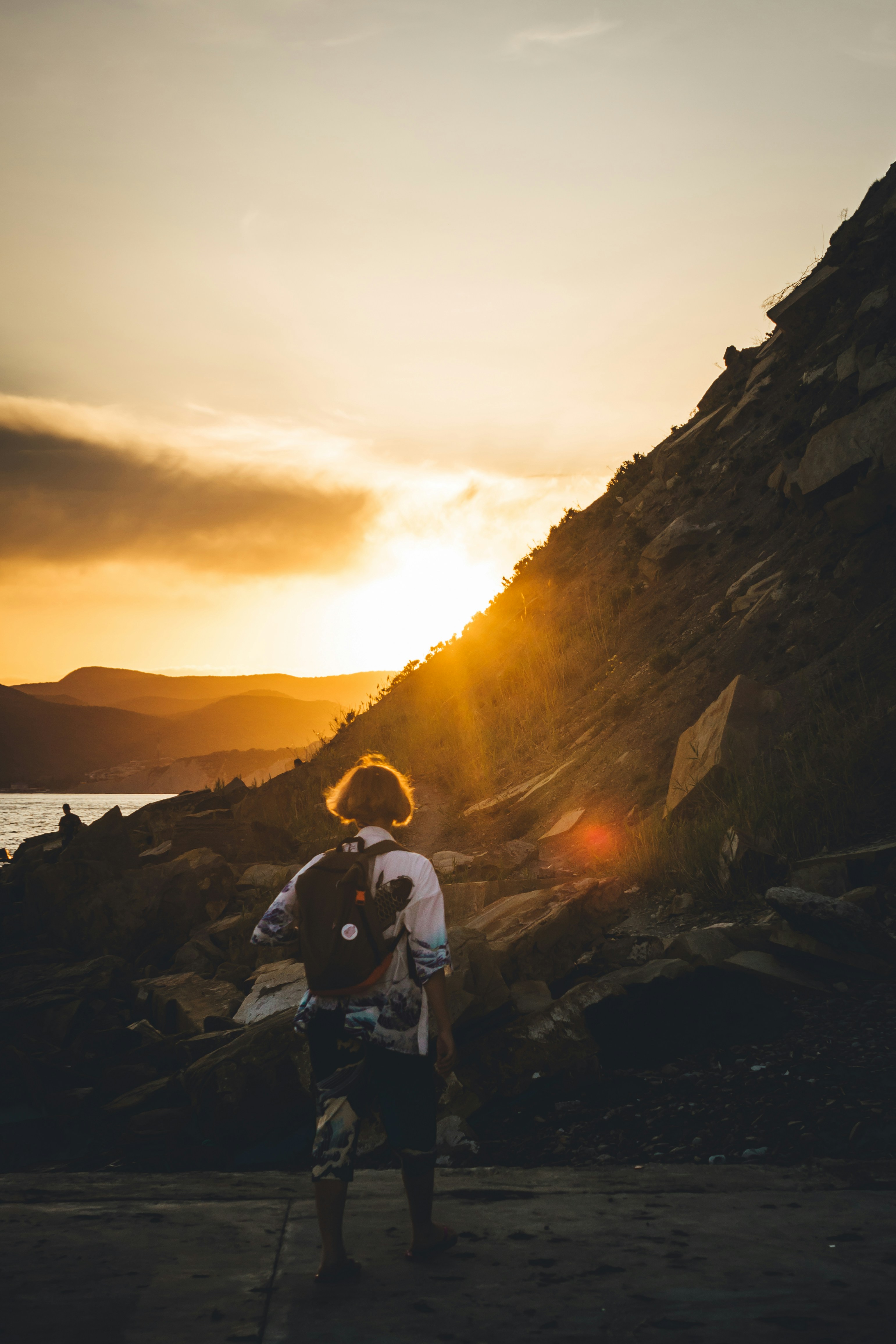 夕暮れ時に岩の上に座る青いジャケットの男