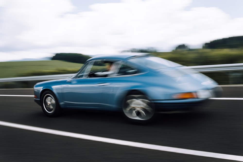 blue sedan on gray asphalt road during daytime