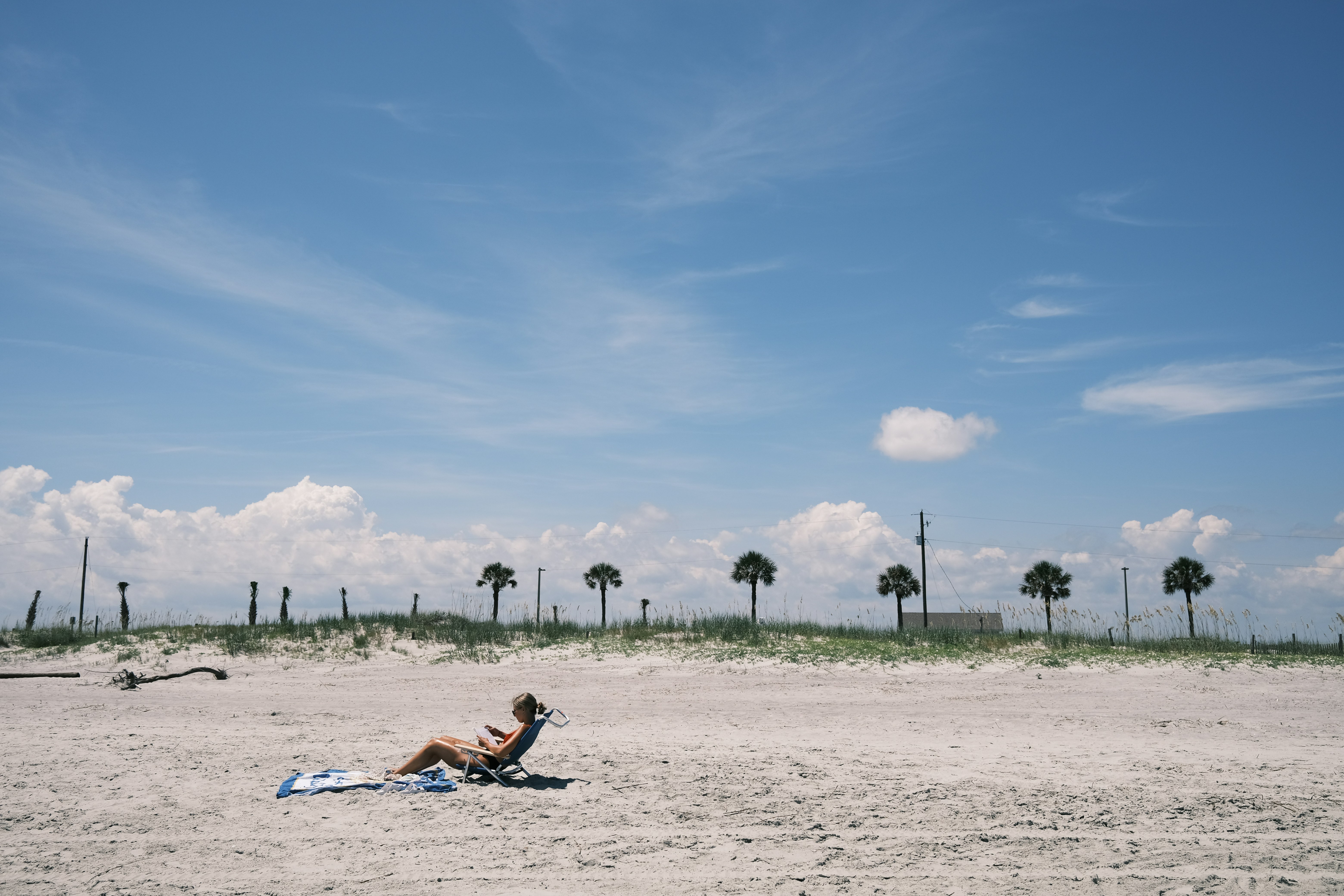woman in white dress lying on white sand under blue sky during daytime