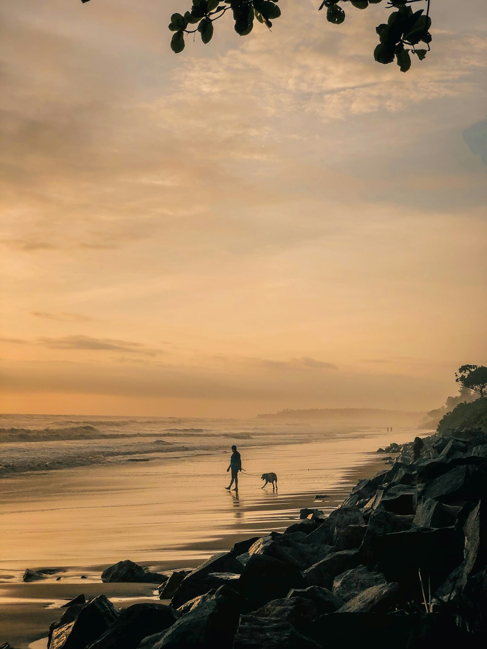 silhouette of 2 people walking on beach during sunset