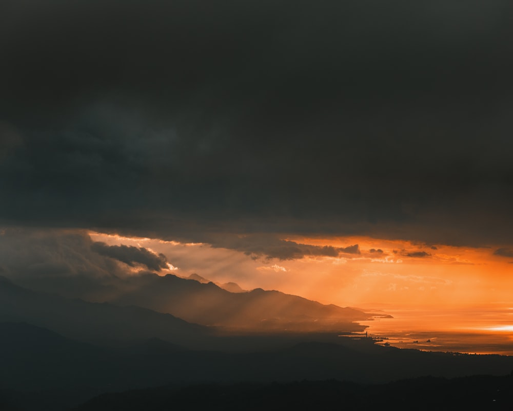 silhouette of mountains under cloudy sky during daytime