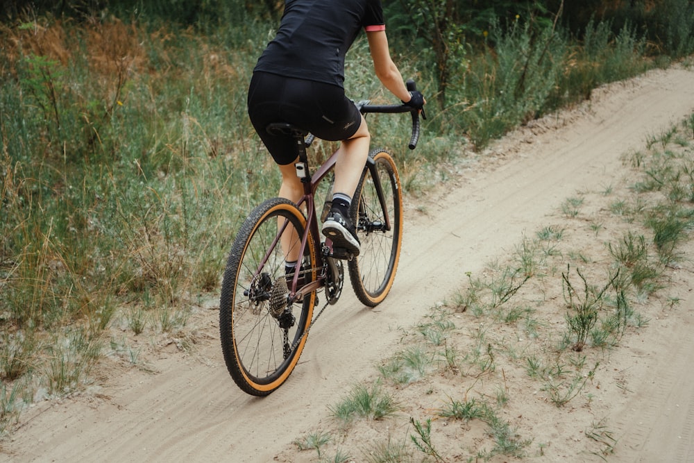 man in black shirt riding on black and white road bike