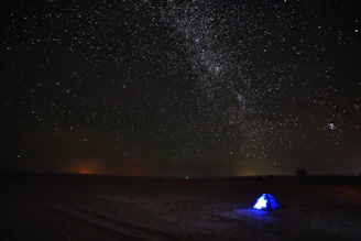 A sleeping bag rolled out under a star-filled sky on a clear camping night