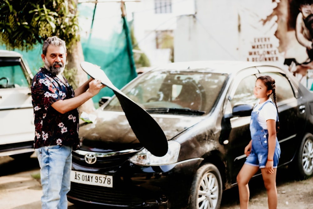 woman in blue and white floral shirt standing beside black honda car