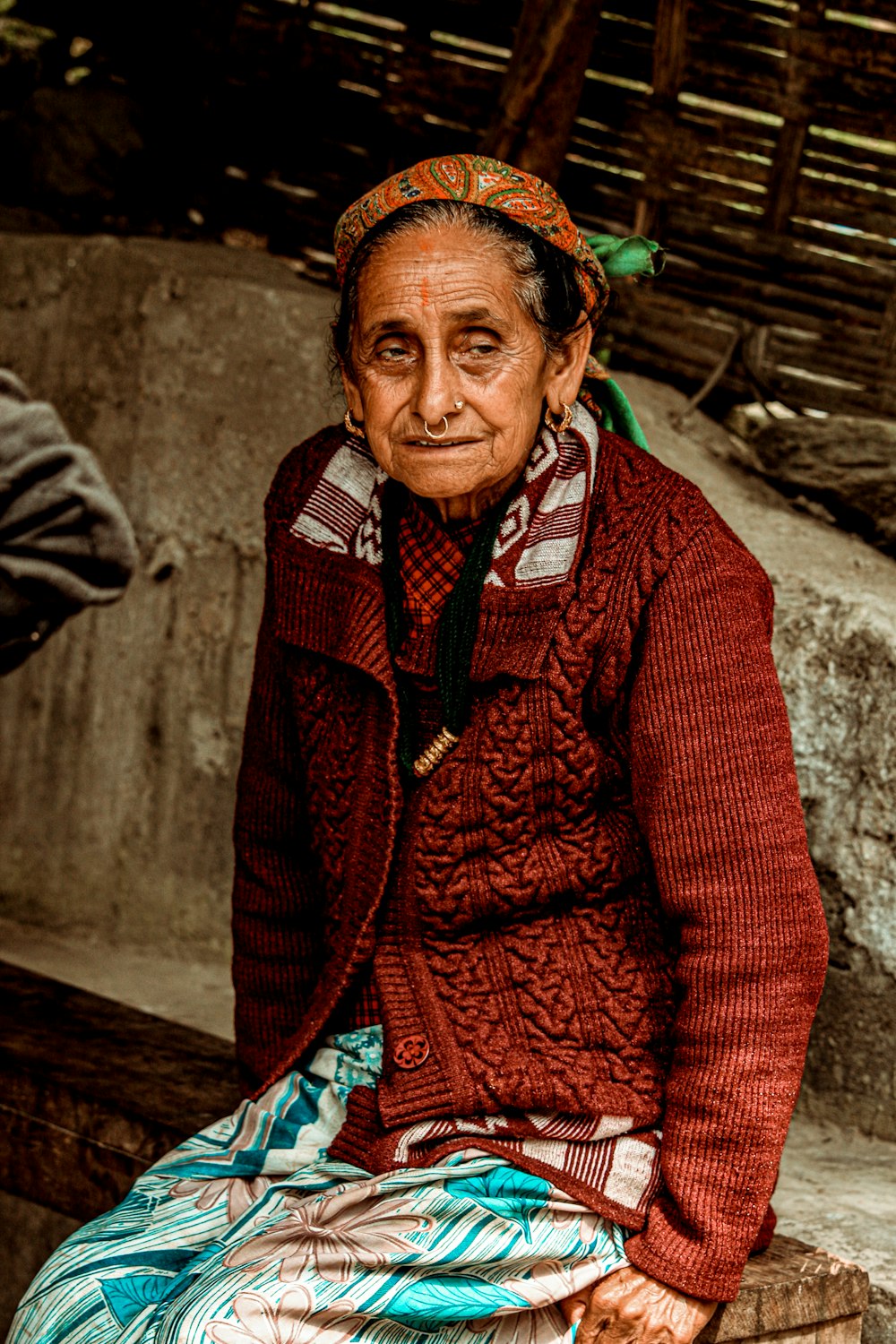 woman in red cardigan standing near brown wooden fence