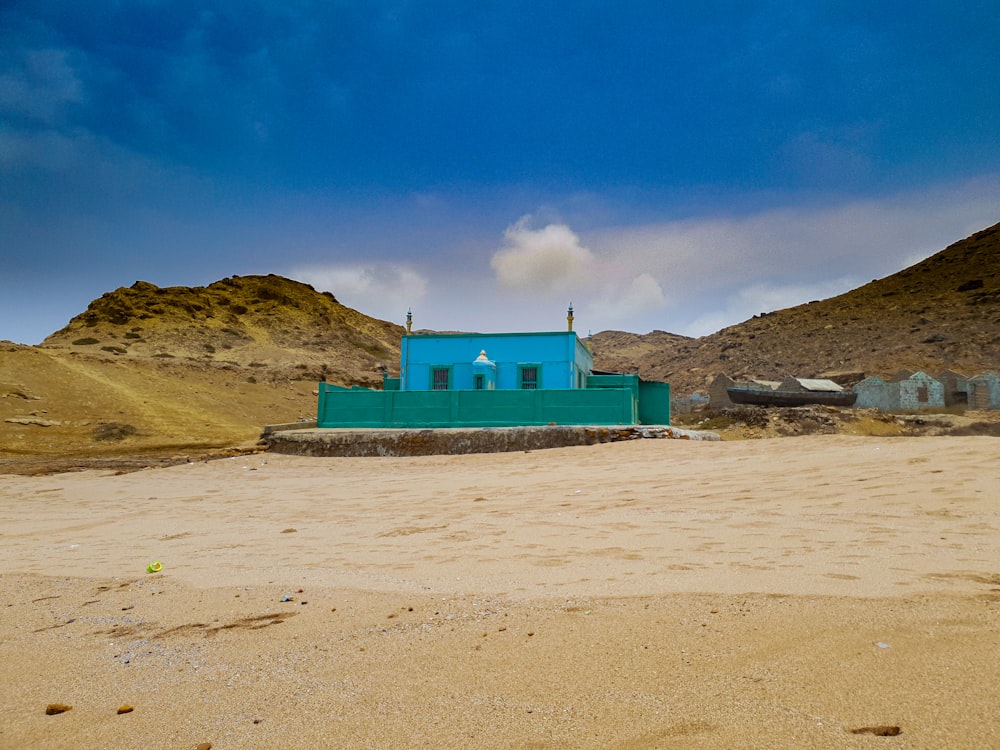 green and white concrete building on white sand under blue sky during daytime