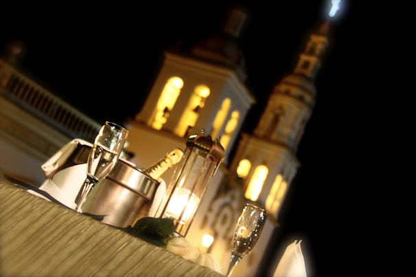 A warm candlelit dinner setup for two on a small balcony overlooking Paris rooftops.