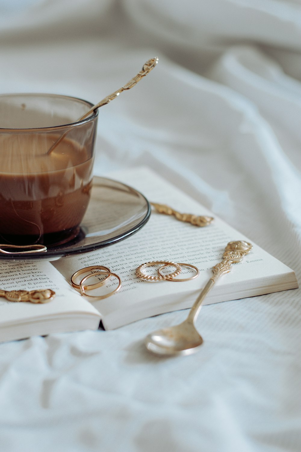 clear glass teacup on saucer with silver spoon