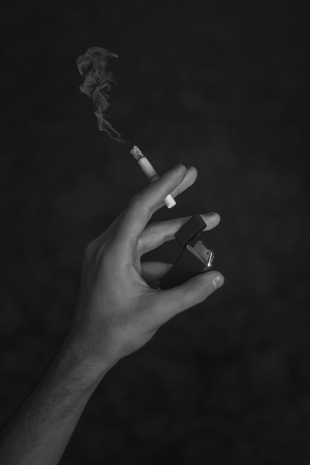 grayscale photo of person holding cigarette stick