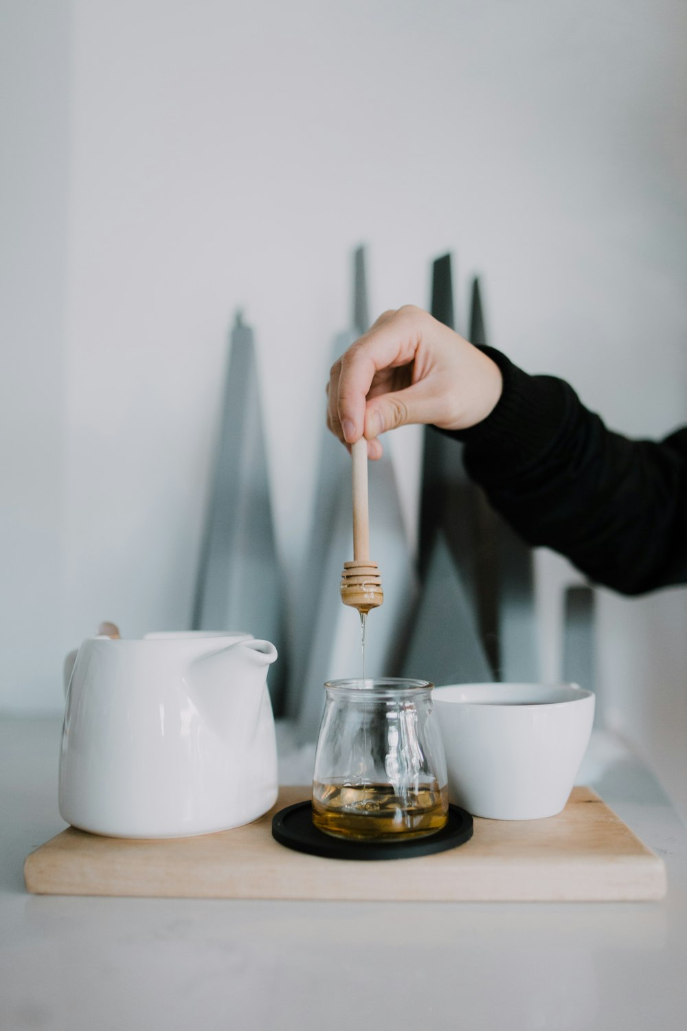 person pouring white liquid on clear glass cup