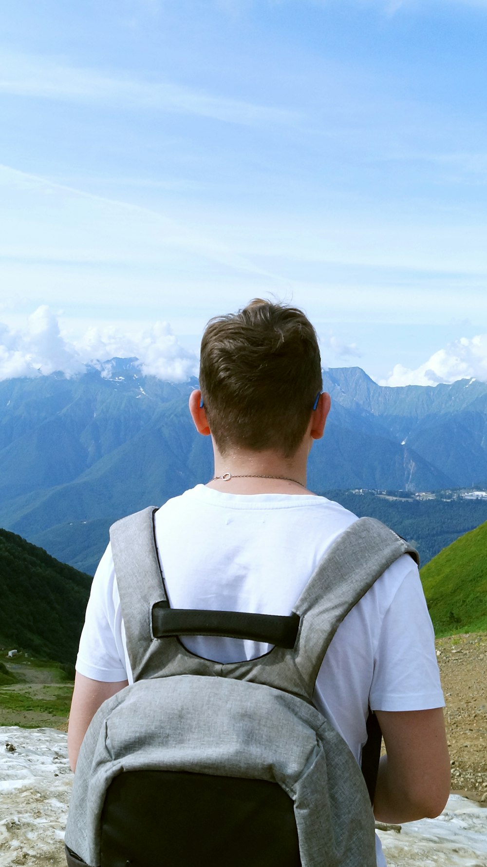 man in white shirt sitting on black chair looking at green mountains during daytime