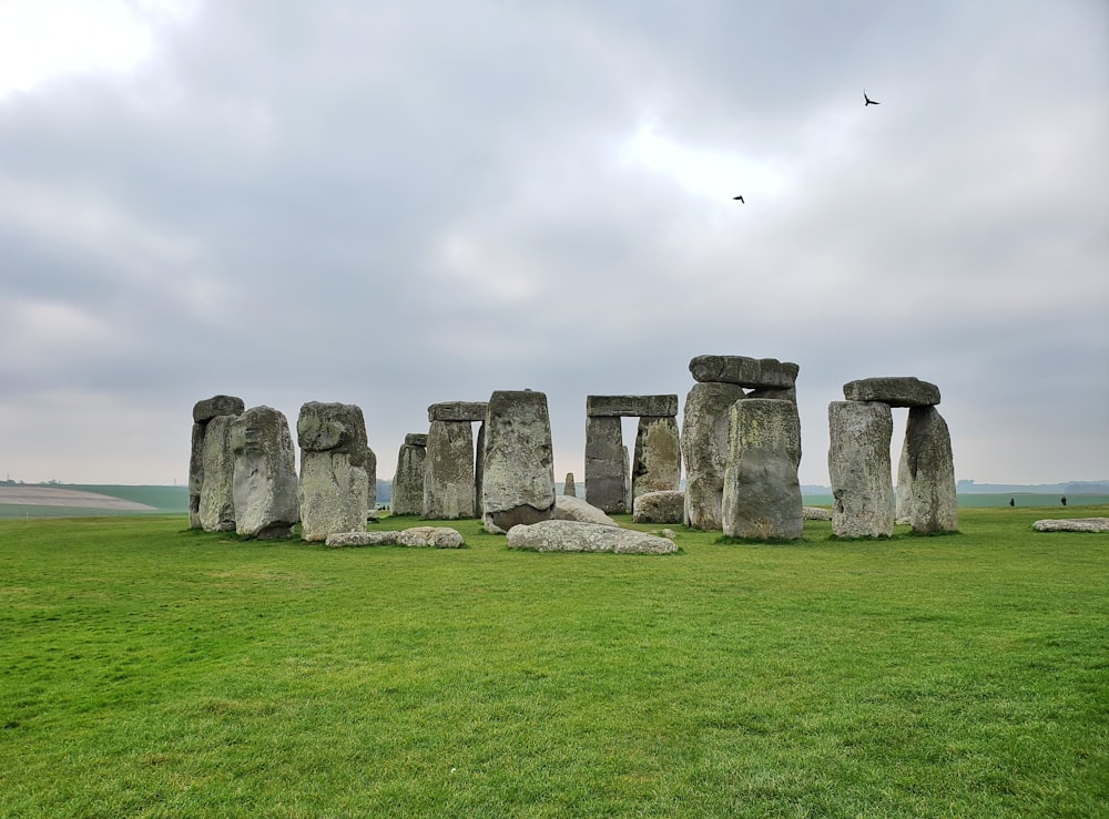 gray rock formation on green grass field under white sky during daytime