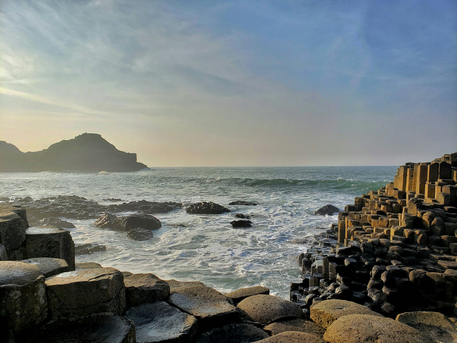 Hexagonal basalt columns of the Giant's Causeway meeting the sea at golden hour, Northern Ireland