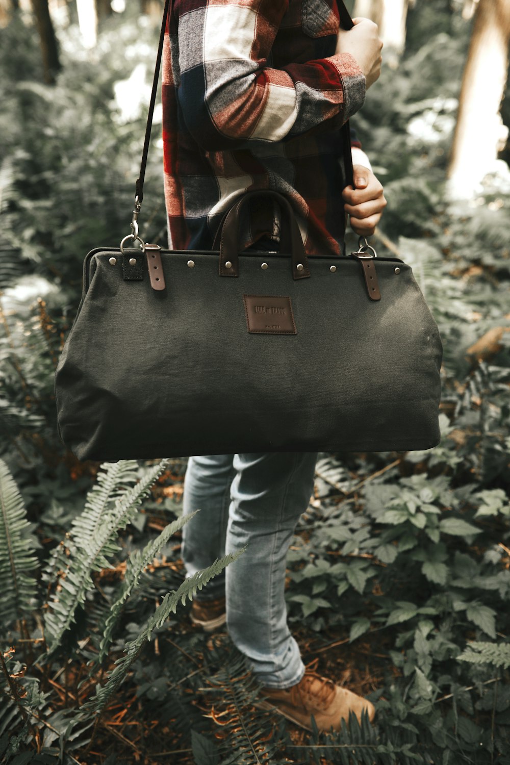 person in blue denim jeans and black leather handbag