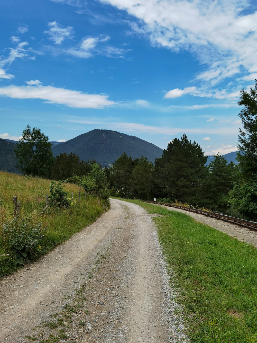 green grass field near mountain under blue sky during daytime