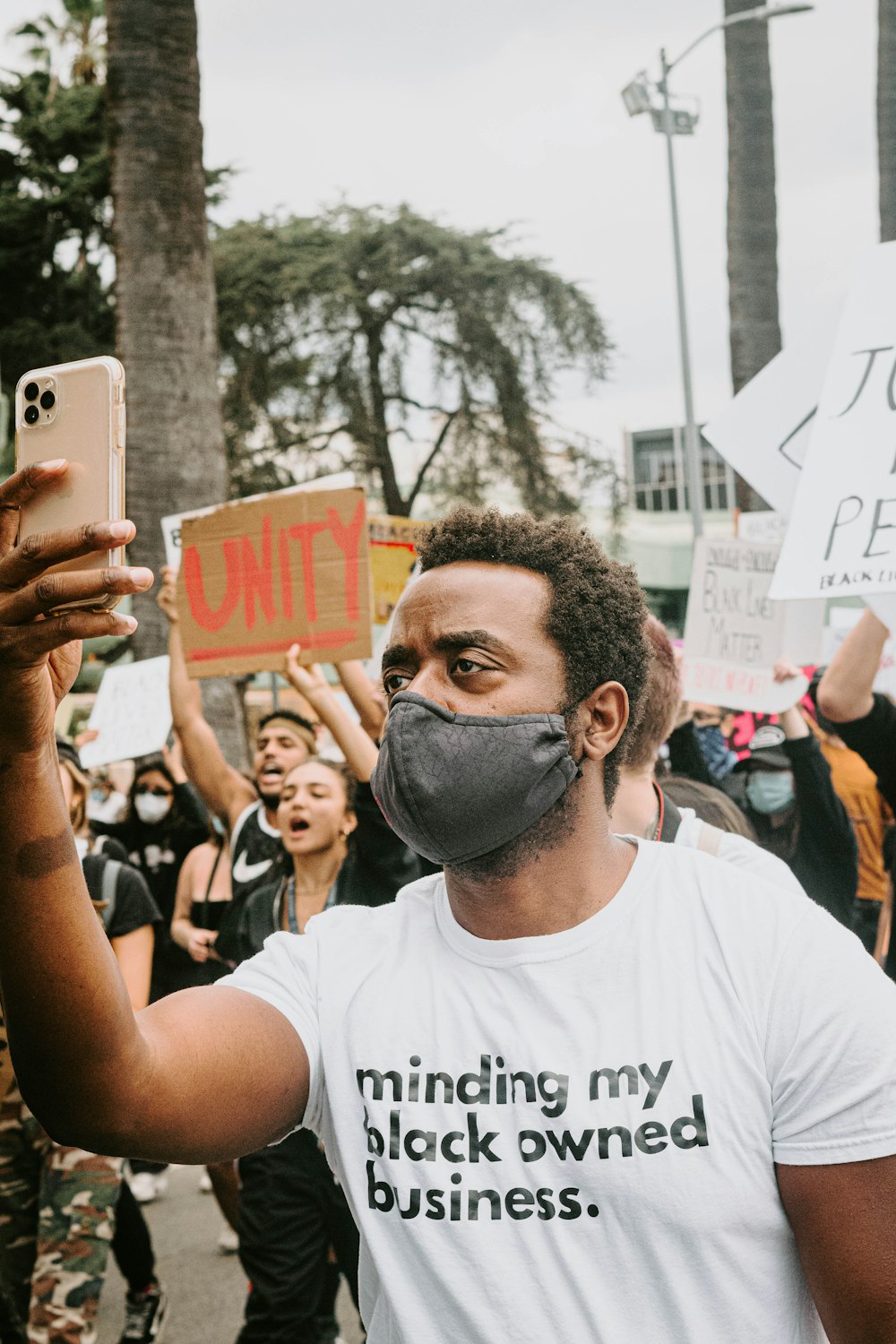 man in white crew neck t-shirt holding white smartphone